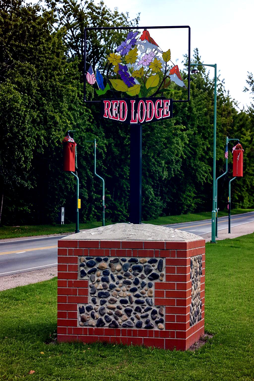 Colourful village metal sign set in red brick base for Red Lodge